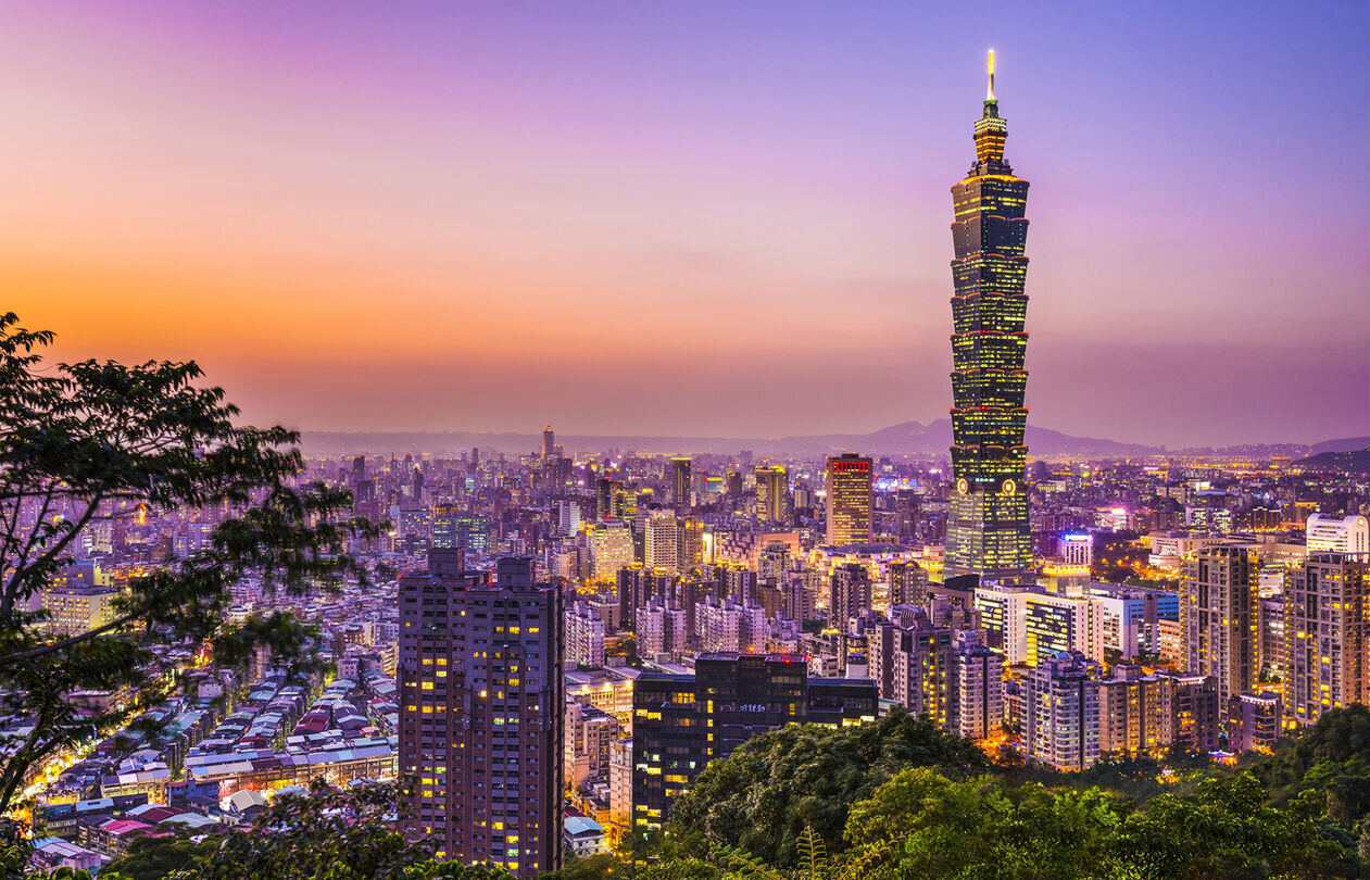 固件安全优化 300 A vibrant city skyline at sunset, featuring a tall tower amidst illuminated buildings and a colorful sky.
